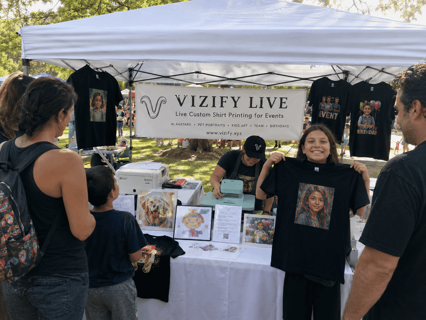 Young guest beaming as she holds up the portrait shirt she designed at the booth